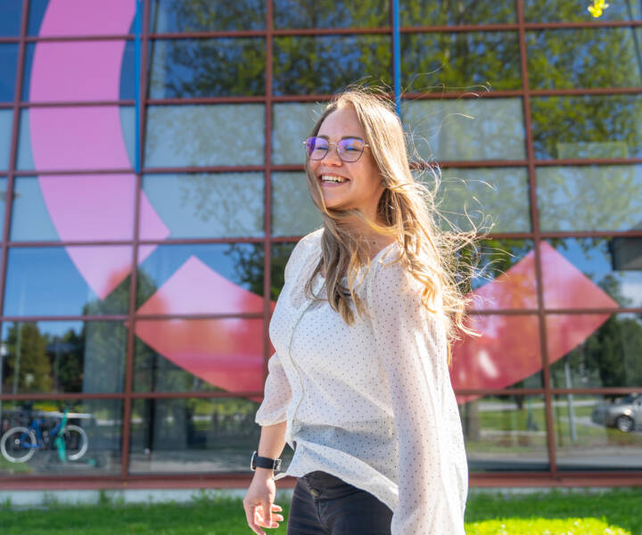 Female student standing in front of Centria Kokkola campus laughing