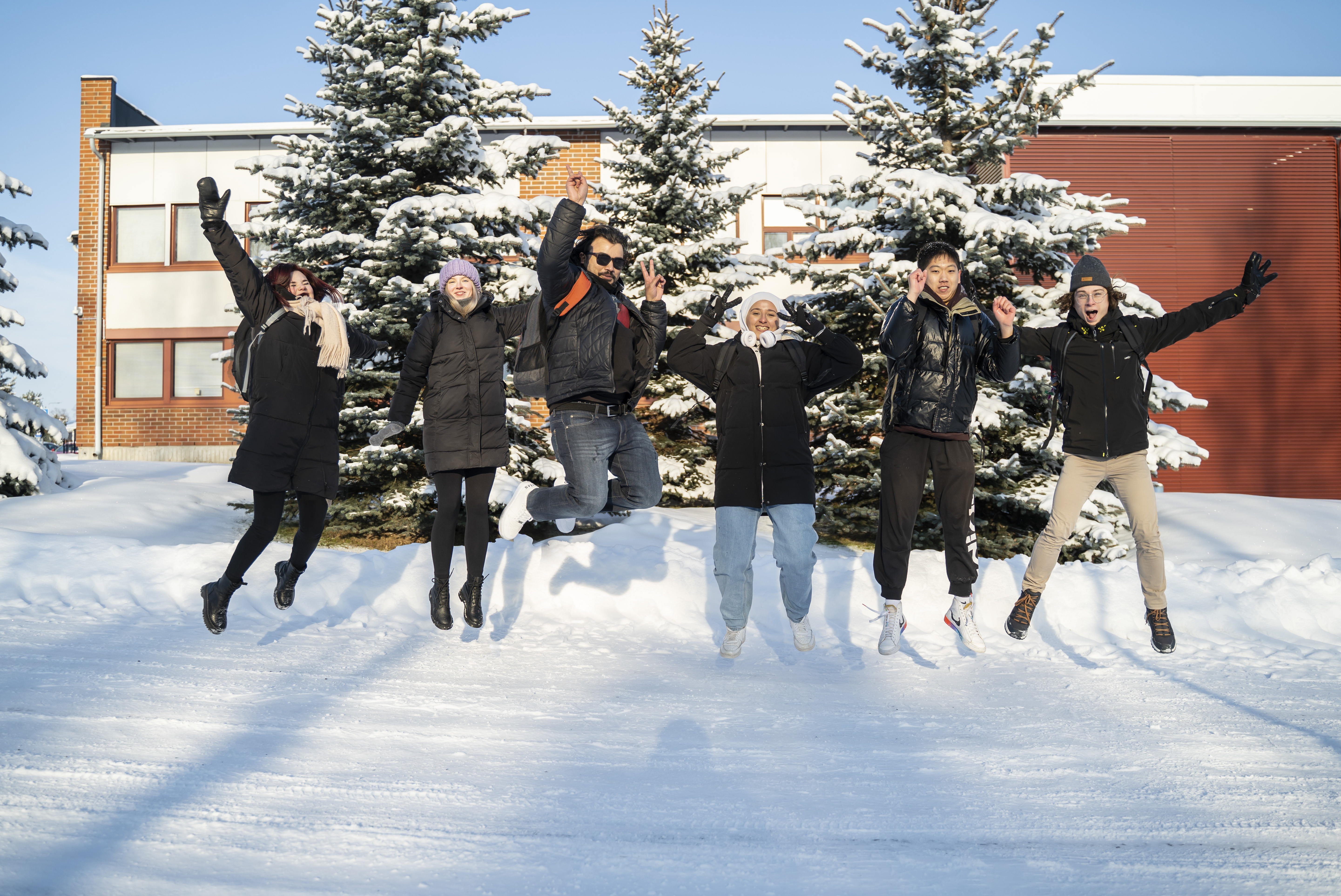Ryhmä opiskelijoita kuvattuna Talonpojankadun kampuksen pihalla talviaikaan.