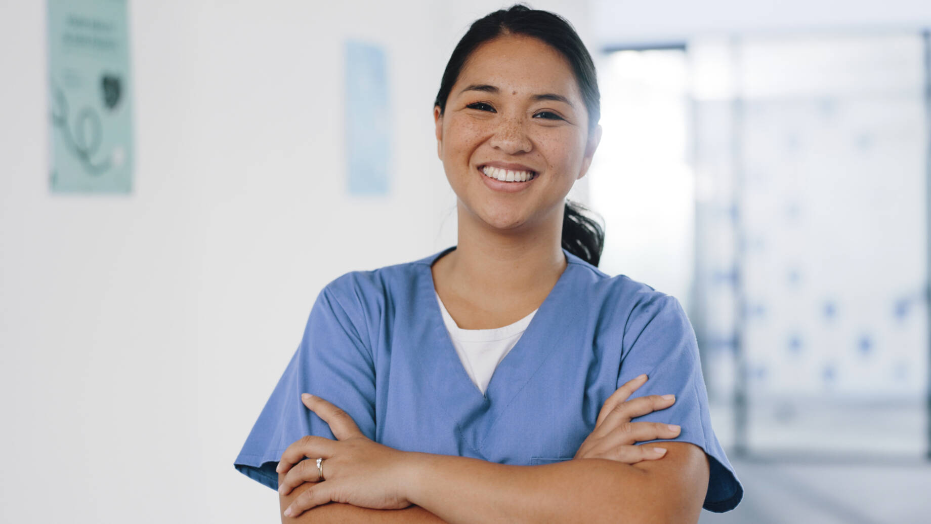 Kaakkois-Aasialainen sairaanhoitaja poseeraa hymyillen kameralle