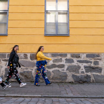 Kolme opiskelijaa kävelee Kokkolassa kadulla opiskelijahaalarit päällään ja hymyilevät