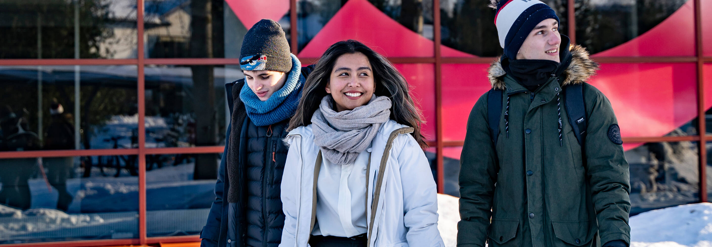 Three students pictured in front of the Talonpojankatu Campus during winter