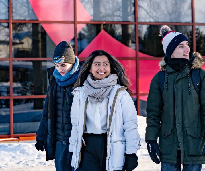 Three students pictured in front of the Talonpojankatu Campus during winter