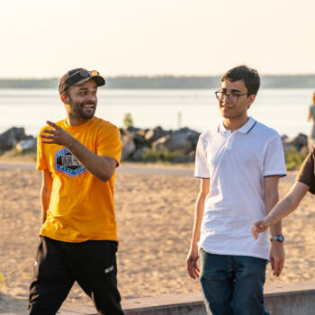 Three international students pictured at a sand beach in Kokkola
