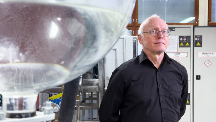 Mies mustassa kauluspaidassa seisoo laboratoriossa