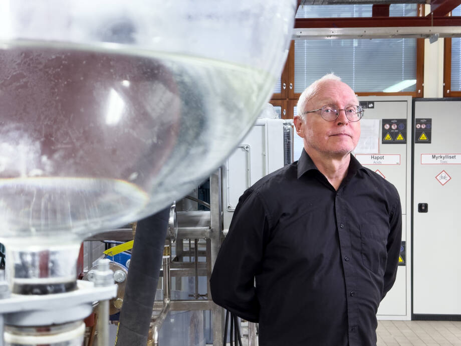 Mies mustassa kauluspaidassa seisoo laboratoriossa