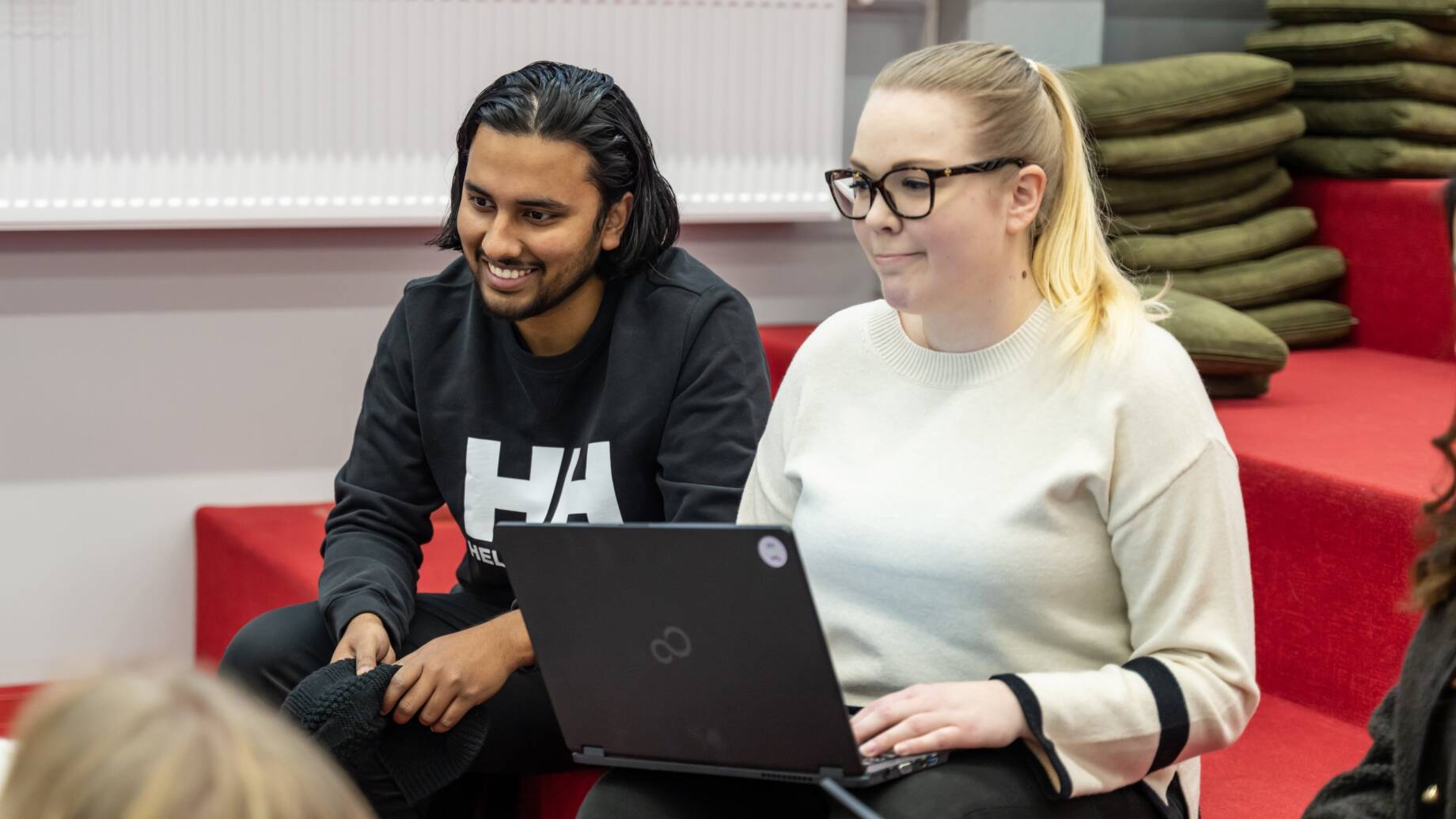students with laptop on red stairs