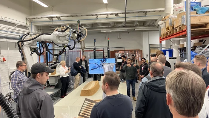 Tapahtuman vieraita ja asiantuntijoita kuvattuna Centrian PlasLab-kehitysympäristössä. Kuvassa näkyy ihmisten lisäksi suuri teollisuusrobotti sekä 3D-tulostettu ja robotisoidusti jyrsitty muotti