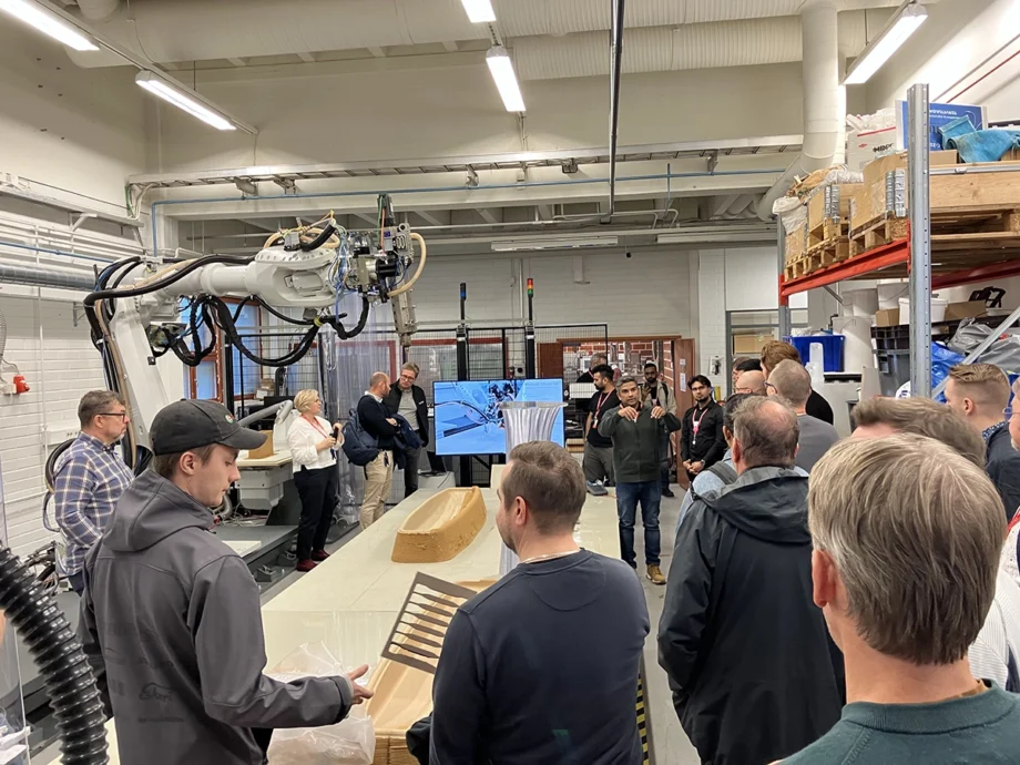 Tapahtuman vieraita ja asiantuntijoita kuvattuna Centrian PlasLab-kehitysympäristössä. Kuvassa näkyy ihmisten lisäksi suuri teollisuusrobotti sekä 3D-tulostettu ja robotisoidusti jyrsitty muotti